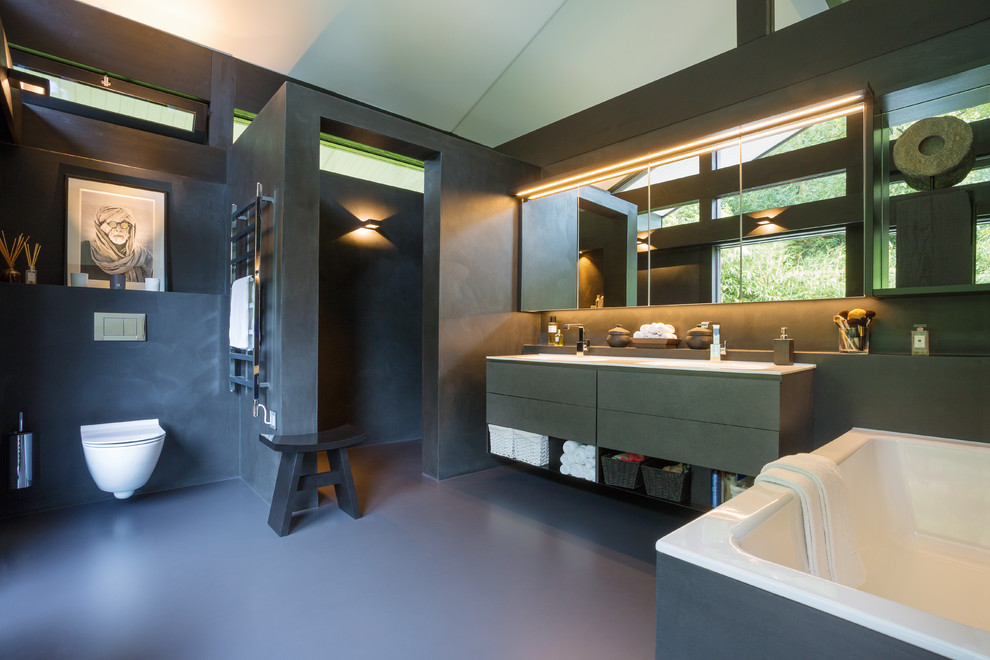 Exemple d'une salle de bain principale tendance de taille moyenne avec un placard à porte plane, des portes de placard noires, WC suspendus, un mur noir et un sol noir.