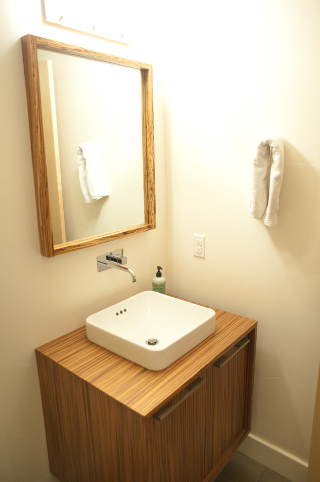 Aménagement d'une salle de bain moderne en bois brun avec une vasque, un placard en trompe-l'oeil et un plan de toilette en bois.