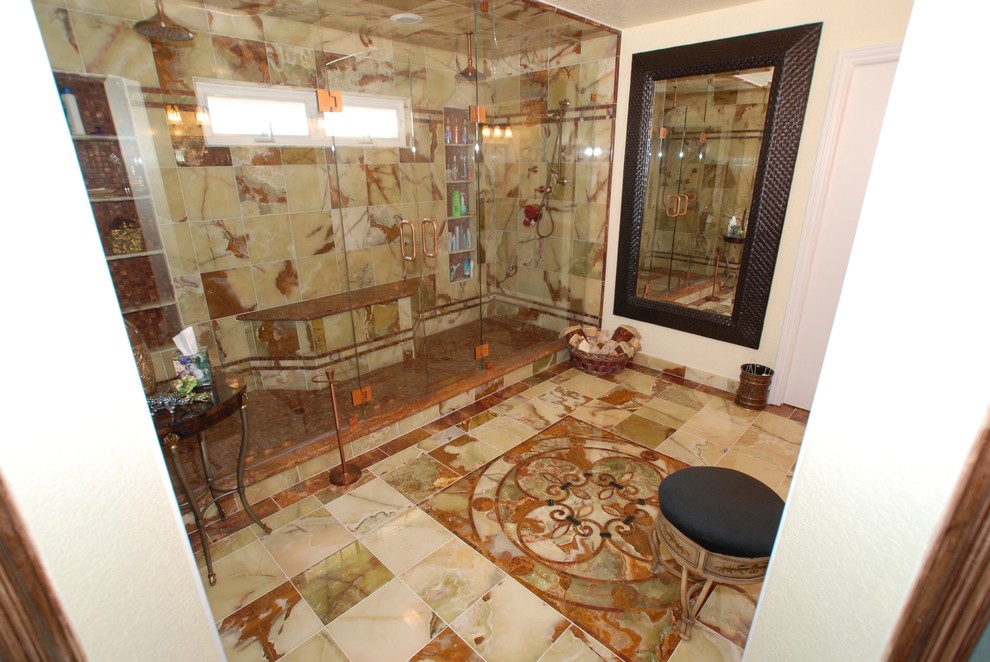 Design ideas for an expansive mediterranean ensuite bathroom in Orange County with a submerged sink, raised-panel cabinets, distressed cabinets, an alcove shower, a two-piece toilet, green tiles, stone tiles, beige walls and marble flooring.
