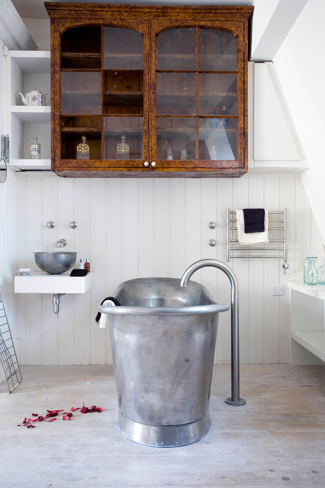 Bild på ett funkis badrum, med skåp i mellenmörkt trä, ett fristående badkar, vita väggar och ljust trägolv