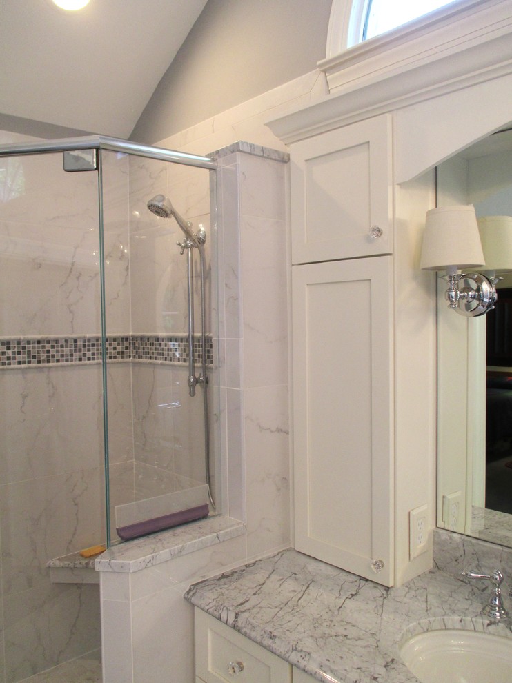 Modelo de cuarto de baño principal clásico con puertas de armario blancas, encimera de mármol, bañera con patas, ducha esquinera, baldosas y/o azulejos de porcelana, paredes grises y suelo de baldosas de porcelana