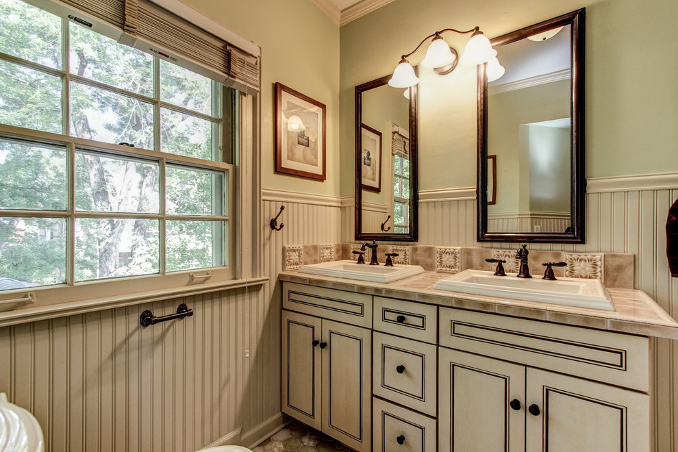 Bild på ett mellanstort vintage badrum med dusch, med luckor med upphöjd panel, vita skåp, en toalettstol med separat cisternkåpa, keramikplattor, gröna väggar, klinkergolv i keramik, ett nedsänkt handfat och kaklad bänkskiva