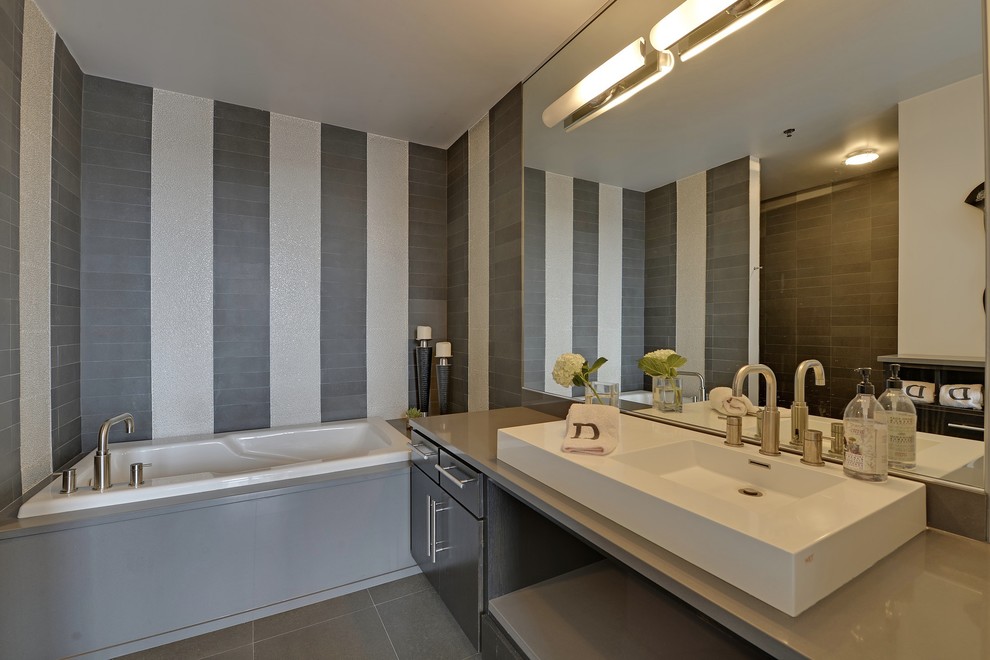 Esempio di una stanza da bagno contemporanea con lavabo a bacinella, ante lisce, ante in legno bruno, top in quarzite, vasca da incasso, doccia aperta, piastrelle grigie, piastrelle in pietra e top grigio