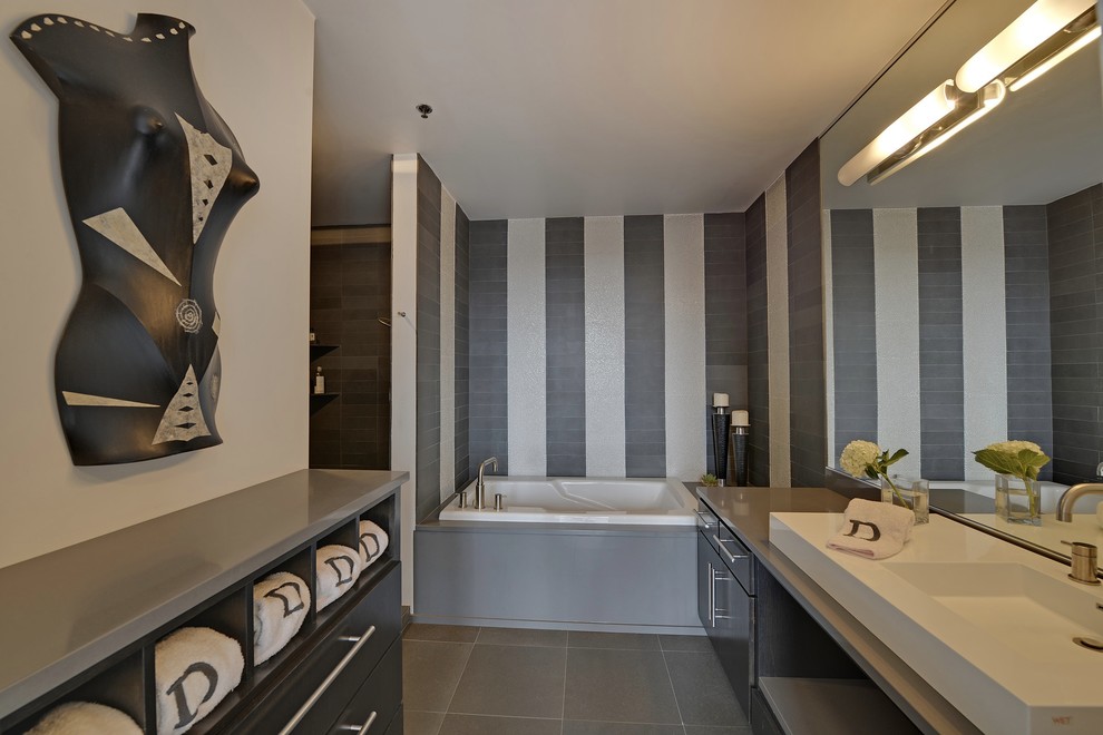 Cette image montre une salle de bain design en bois foncé avec une vasque, un placard en trompe-l'oeil, un plan de toilette en quartz, une baignoire posée, une douche ouverte, WC séparés, un carrelage gris et un carrelage de pierre.