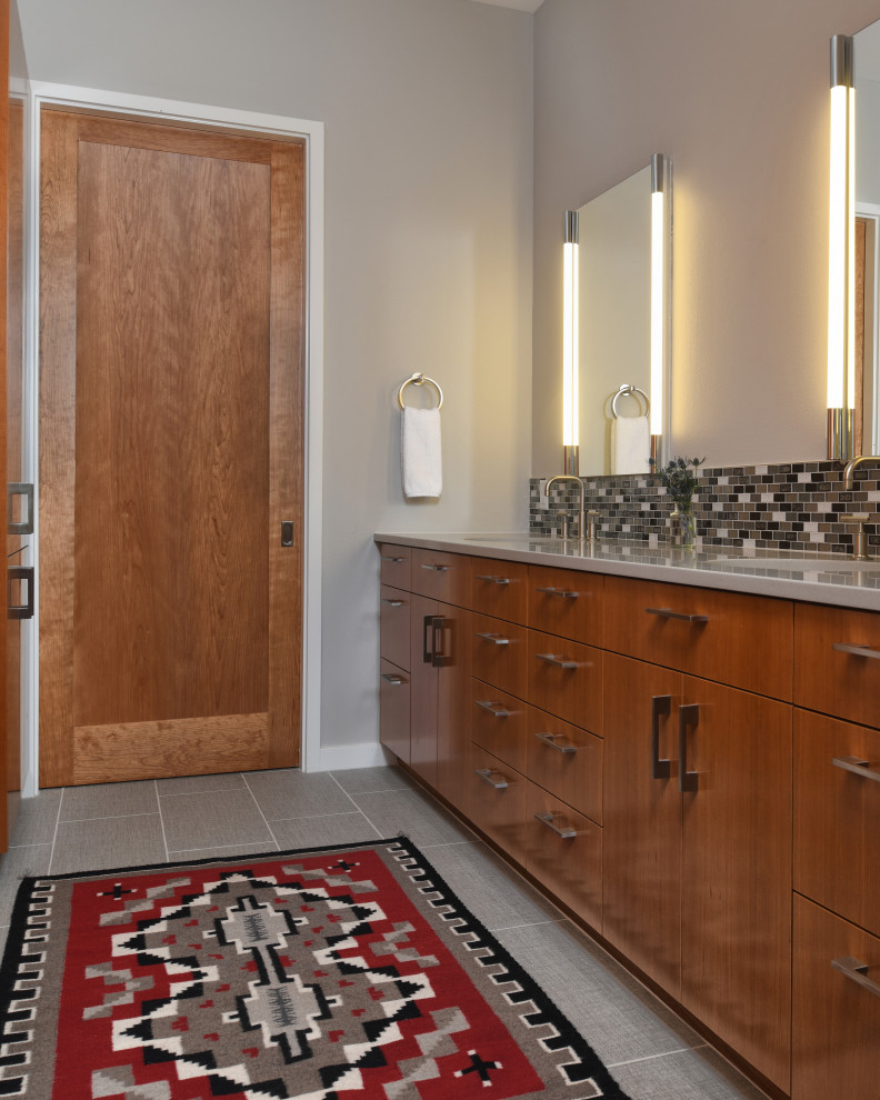 Exemple d'une salle de bain principale chic en bois brun de taille moyenne avec un placard à porte plane, une douche à l'italienne, WC séparés, un carrelage gris, des carreaux de porcelaine, un mur gris, un lavabo encastré, un plan de toilette en surface solide, une cabine de douche à porte battante, un plan de toilette gris, meuble double vasque, meuble-lavabo encastré, un sol en carrelage de porcelaine, un sol gris et un banc de douche.