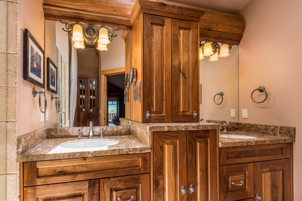 Immagine di una stanza da bagno padronale rustica di medie dimensioni con ante con bugna sagomata, ante in legno scuro, pareti beige, lavabo sottopiano, top in granito e top marrone