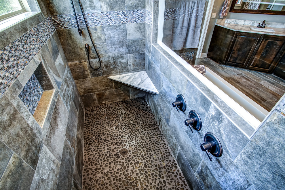 Exempel på ett mellanstort klassiskt en-suite badrum, med luckor med upphöjd panel, skåp i mörkt trä, ett fristående badkar, en kantlös dusch, en toalettstol med hel cisternkåpa, brun kakel, kakel i småsten, grå väggar, klinkergolv i porslin, ett undermonterad handfat och marmorbänkskiva