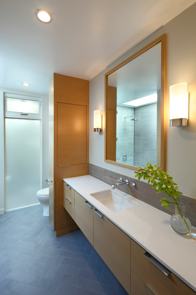 Aménagement d'une grande salle de bain principale contemporaine en bois brun avec un lavabo encastré, un placard à porte plane, un carrelage gris, un mur blanc, un sol en carrelage de céramique et un plan de toilette en surface solide.