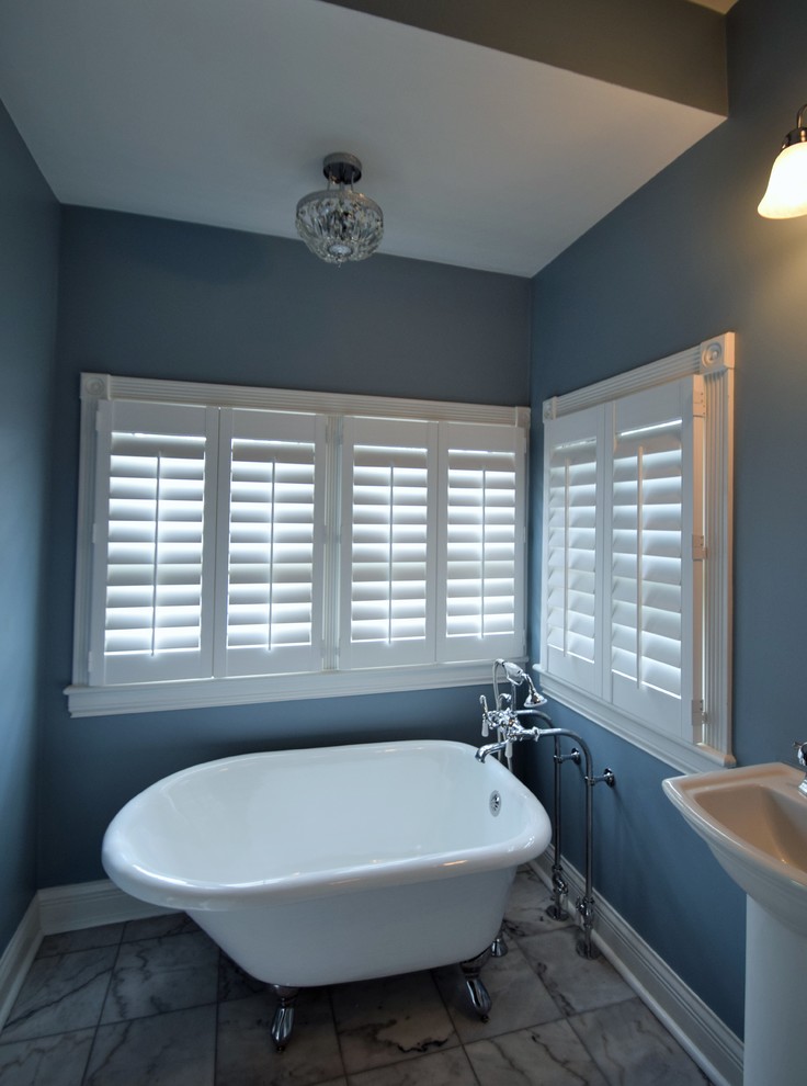 Cette photo montre une salle de bain principale éclectique de taille moyenne avec une baignoire sur pieds, WC à poser, un mur bleu et un lavabo de ferme.
