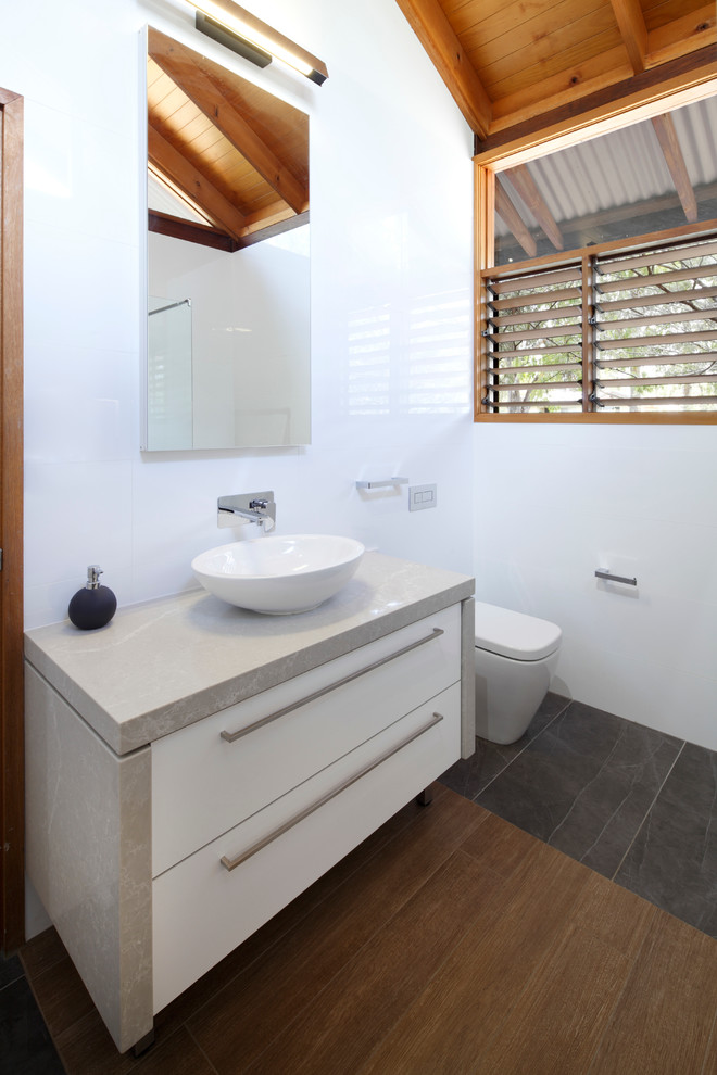 Badezimmer mit Aufsatzwaschbecken, flächenbündigen Schrankfronten, weißen Schränken, weißer Wandfarbe und braunem Holzboden in Adelaide