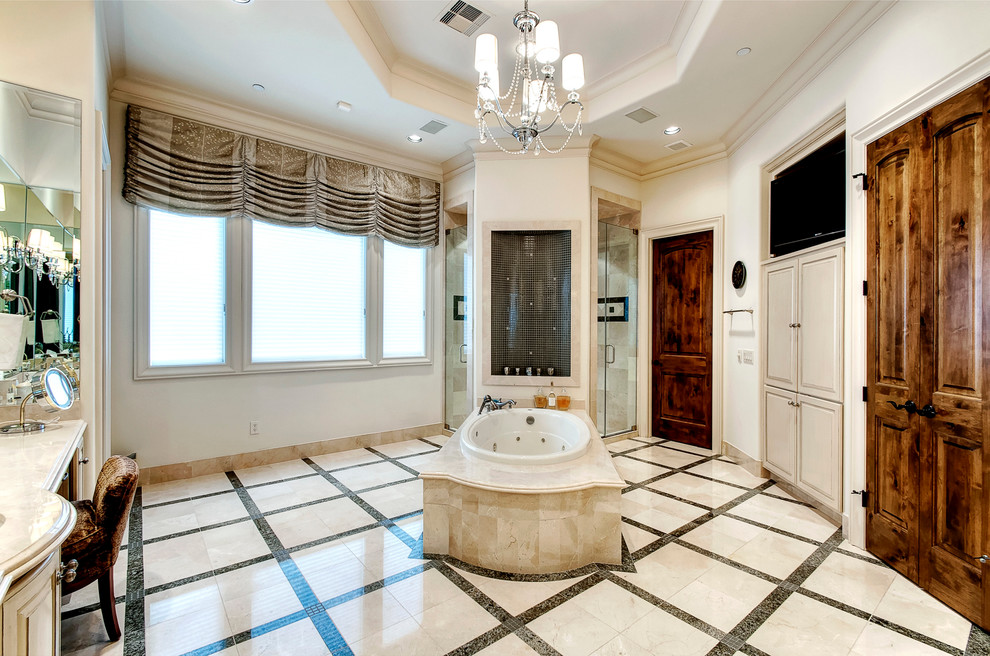 This is an example of a large classic ensuite bathroom in Houston with a submerged sink, freestanding cabinets, distressed cabinets, marble worktops, a built-in bath, a double shower, a two-piece toilet, beige tiles, stone tiles, beige walls, marble flooring, beige floors and a hinged door.