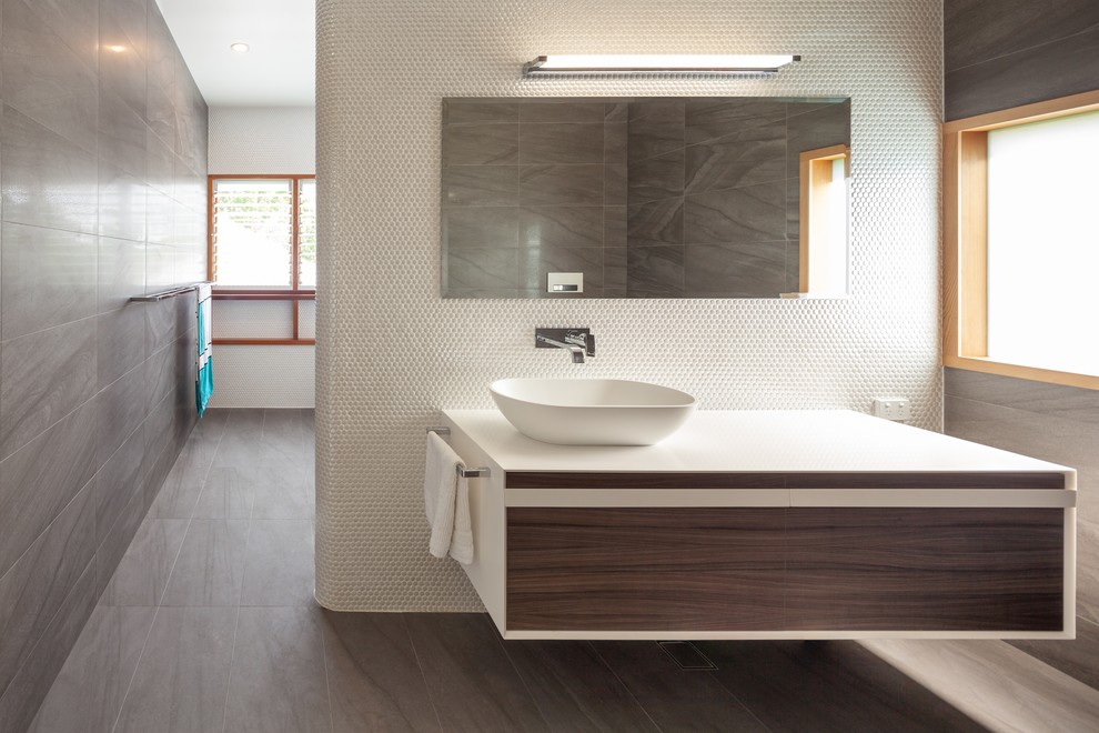 Idéer för att renovera ett stort funkis vit vitt en-suite badrum, med släta luckor, skåp i mörkt trä, ett fristående badkar, en öppen dusch, en vägghängd toalettstol, svart och vit kakel, porslinskakel, vita väggar, klinkergolv i porslin, ett konsol handfat, bänkskiva i akrylsten, grått golv och med dusch som är öppen