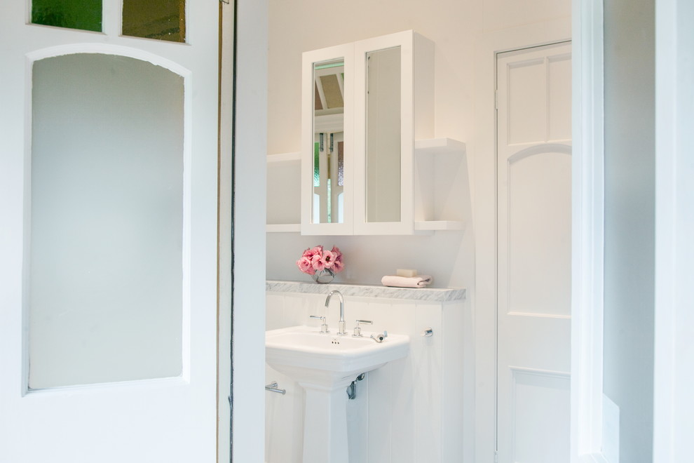 Стильный дизайн: ванная комната среднего размера в викторианском стиле с стеклянными фасадами, белыми фасадами, отдельно стоящей ванной, открытым душем, инсталляцией, белой плиткой, белыми стенами, полом из керамогранита, душевой кабиной, раковиной с пьедесталом, мраморной столешницей, белым полом и открытым душем - последний тренд
