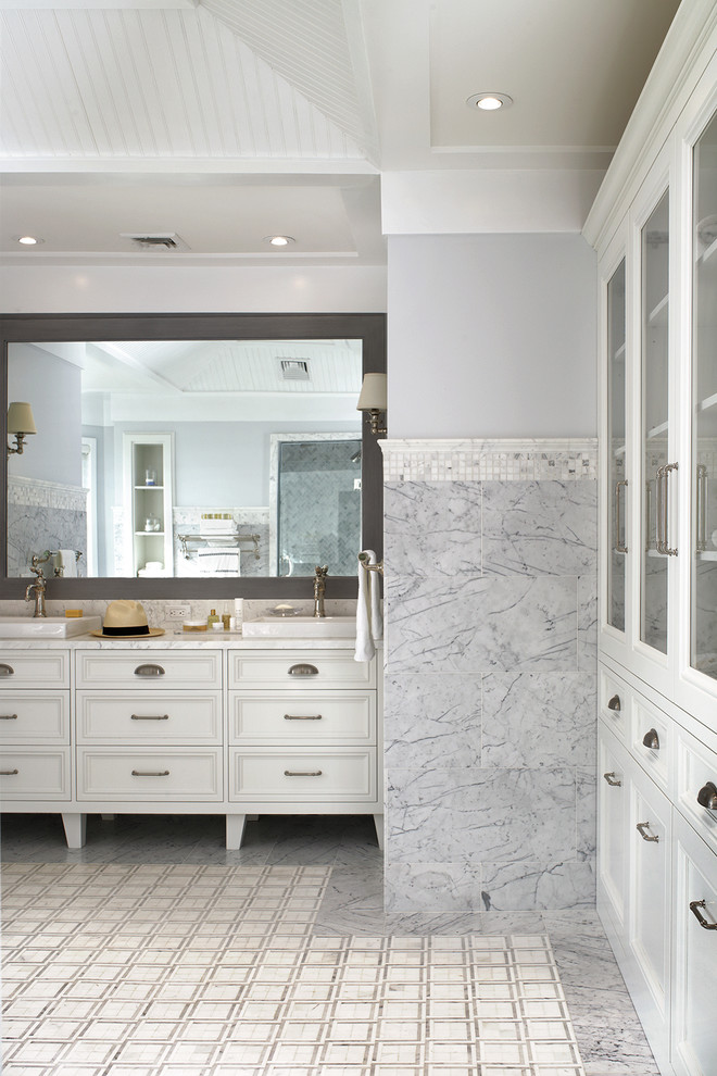 Klassisk inredning av ett stort en-suite badrum, med luckor med glaspanel, vita skåp, ett fristående badkar, stenkakel, grå väggar, dusch med gångjärnsdörr, en toalettstol med separat cisternkåpa och grått golv