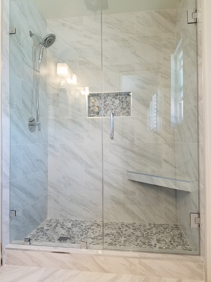 Example of a minimalist marble floor and gray floor alcove shower design in Orange County with a hinged shower door