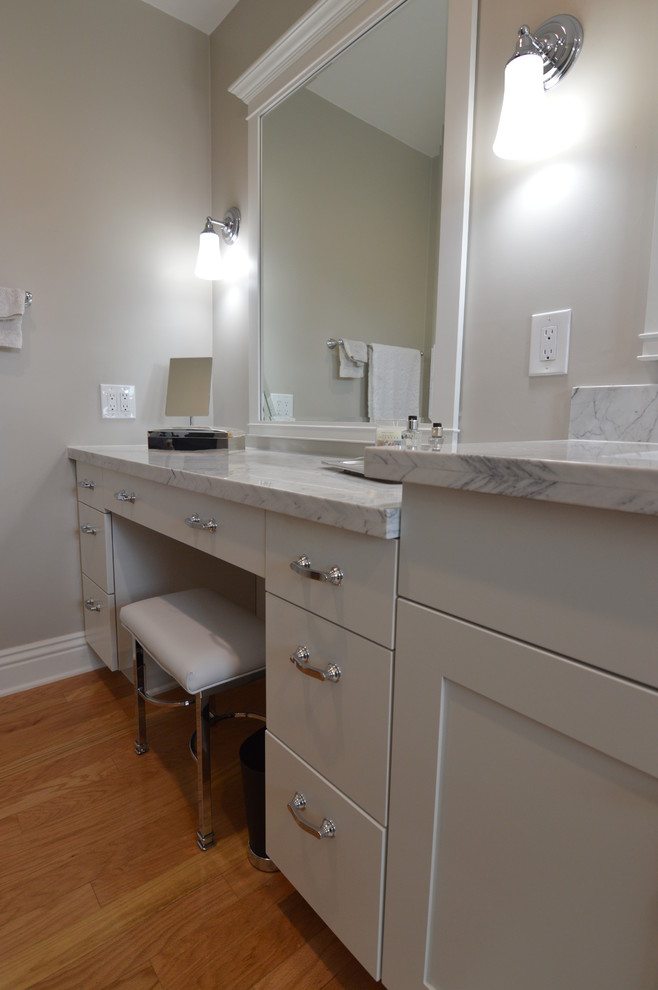 Foto de cuarto de baño principal tradicional renovado de tamaño medio con armarios estilo shaker, puertas de armario blancas, paredes grises, encimera de mármol, ducha empotrada, suelo de madera clara y lavabo bajoencimera