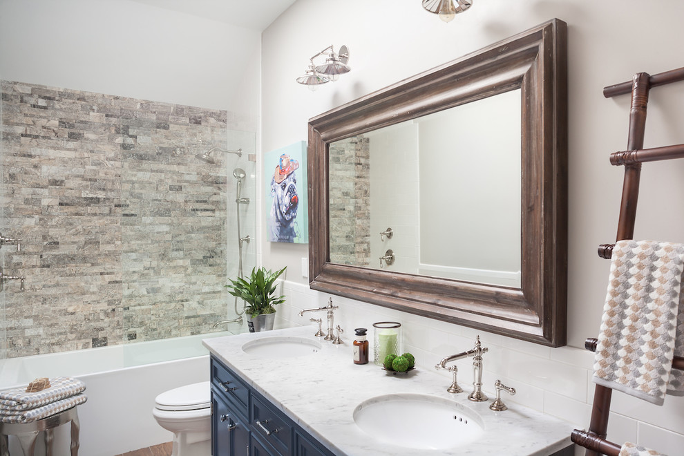 Photo of a medium sized classic family bathroom in New York with blue cabinets, an alcove bath, a shower/bath combination, a one-piece toilet, brown tiles, metro tiles, grey walls, porcelain flooring, a submerged sink and marble worktops.