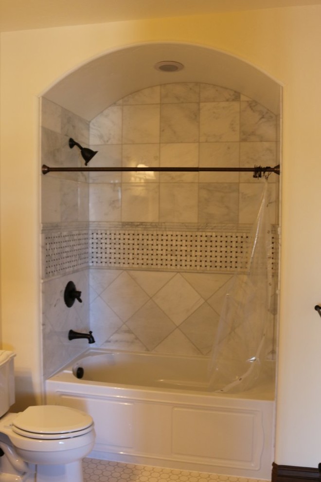 Idee per una stanza da bagno con doccia country di medie dimensioni con vasca ad alcova, doccia alcova, WC a due pezzi, piastrelle grigie, piastrelle bianche, piastrelle in gres porcellanato, pareti beige e pavimento con piastrelle a mosaico