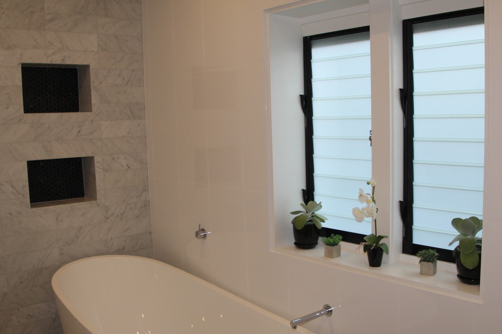 Design ideas for a medium sized contemporary ensuite wet room bathroom in Sydney with glass-front cabinets, white cabinets, a freestanding bath, a wall mounted toilet, black and white tiles, marble tiles, white walls, porcelain flooring, an integrated sink, solid surface worktops and grey floors.