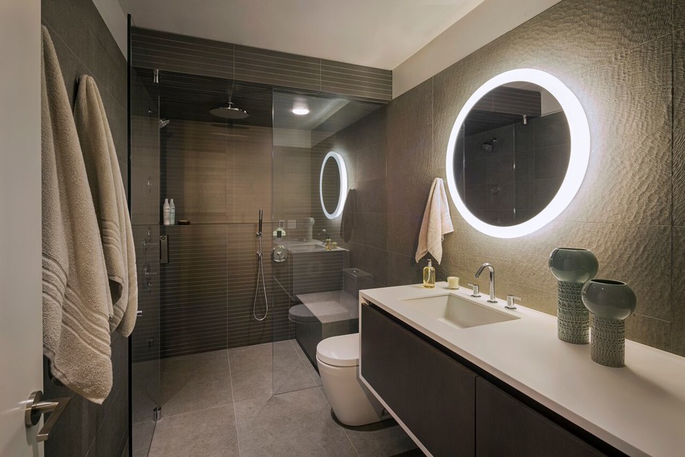 Large minimalist gray tile and porcelain tile porcelain tile walk-in shower photo in Chicago with an undermount sink, solid surface countertops, a one-piece toilet, flat-panel cabinets, dark wood cabinets and gray walls