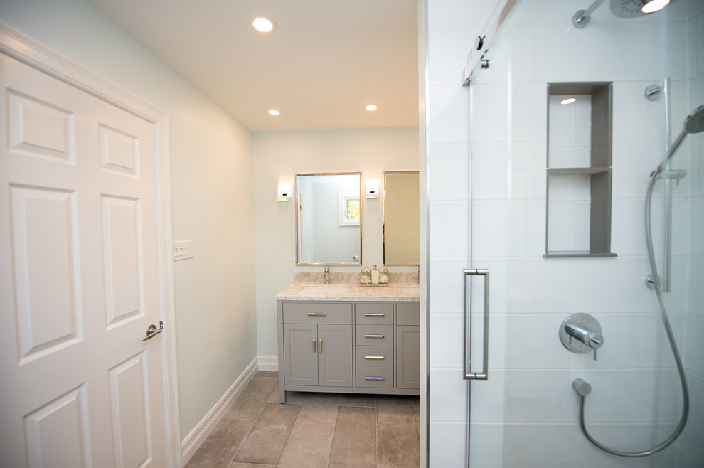 Cette photo montre une salle de bain principale tendance de taille moyenne avec un placard à porte shaker, des portes de placard grises, un carrelage blanc, un plan de toilette en marbre et une cabine de douche à porte coulissante.
