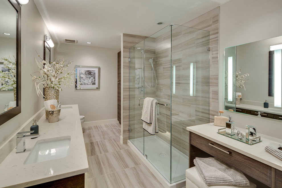 This is an example of a large modern ensuite bathroom in Vancouver with flat-panel cabinets, medium wood cabinets, a corner shower, beige tiles, beige walls, limestone flooring, a submerged sink and quartz worktops.