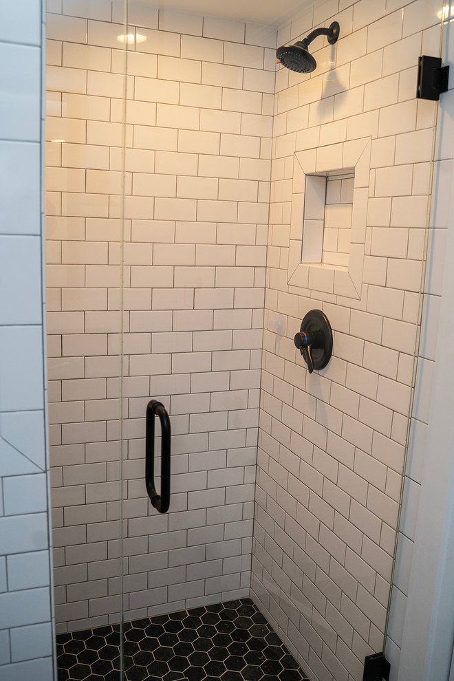 На фото: детская ванная комната среднего размера в стиле неоклассика (современная классика) с душем без бортиков, белой плиткой, белыми стенами, полом из керамической плитки, врезной раковиной, серым полом, душем с распашными дверями, фасадами островного типа, искусственно-состаренными фасадами, отдельно стоящей ванной, раздельным унитазом, керамической плиткой, столешницей из искусственного кварца и черной столешницей с