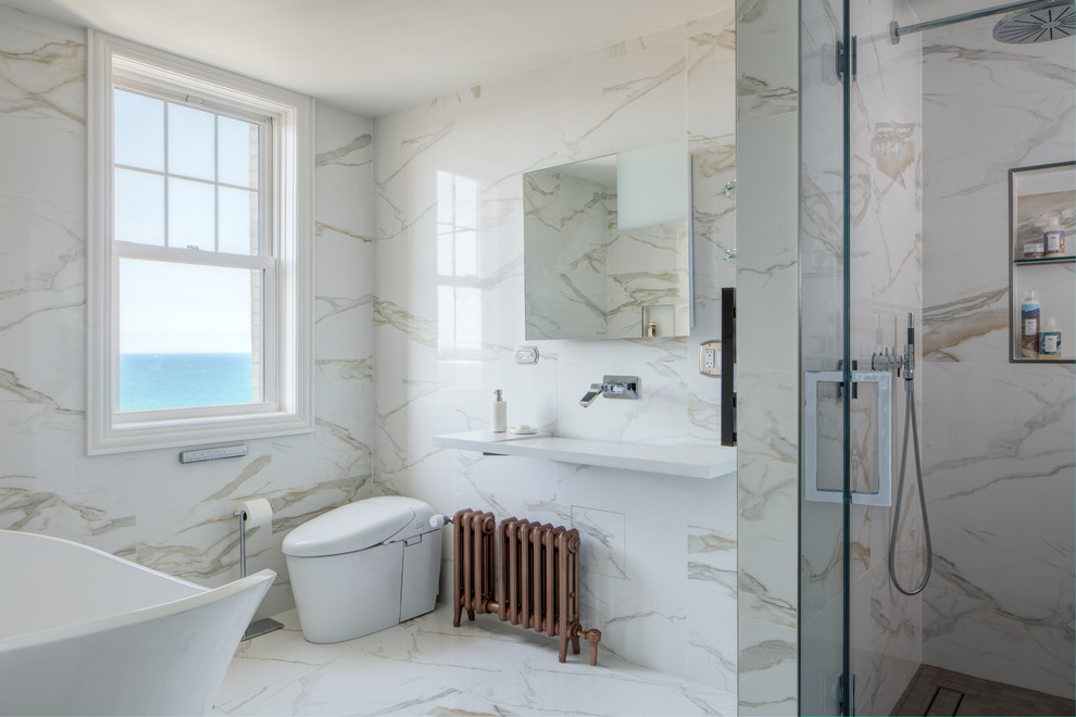 Cette image montre une salle d'eau beige et blanche design avec une baignoire indépendante, une douche d'angle, WC à poser, un carrelage beige, un carrelage blanc, un mur blanc, un lavabo suspendu et un sol blanc.