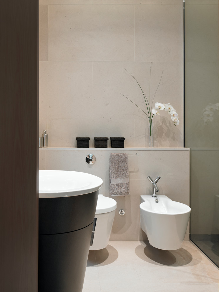 Small contemporary ensuite bathroom in London with freestanding cabinets, dark wood cabinets, a walk-in shower, a bidet, beige tiles, stone tiles, beige walls, limestone flooring, a pedestal sink and limestone worktops.