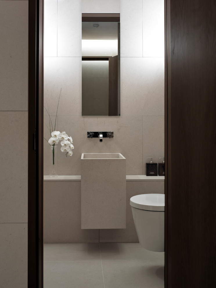 Small contemporary ensuite bathroom in London with freestanding cabinets, dark wood cabinets, a wall mounted toilet, beige tiles, stone tiles, beige walls, limestone flooring, a built-in sink and limestone worktops.