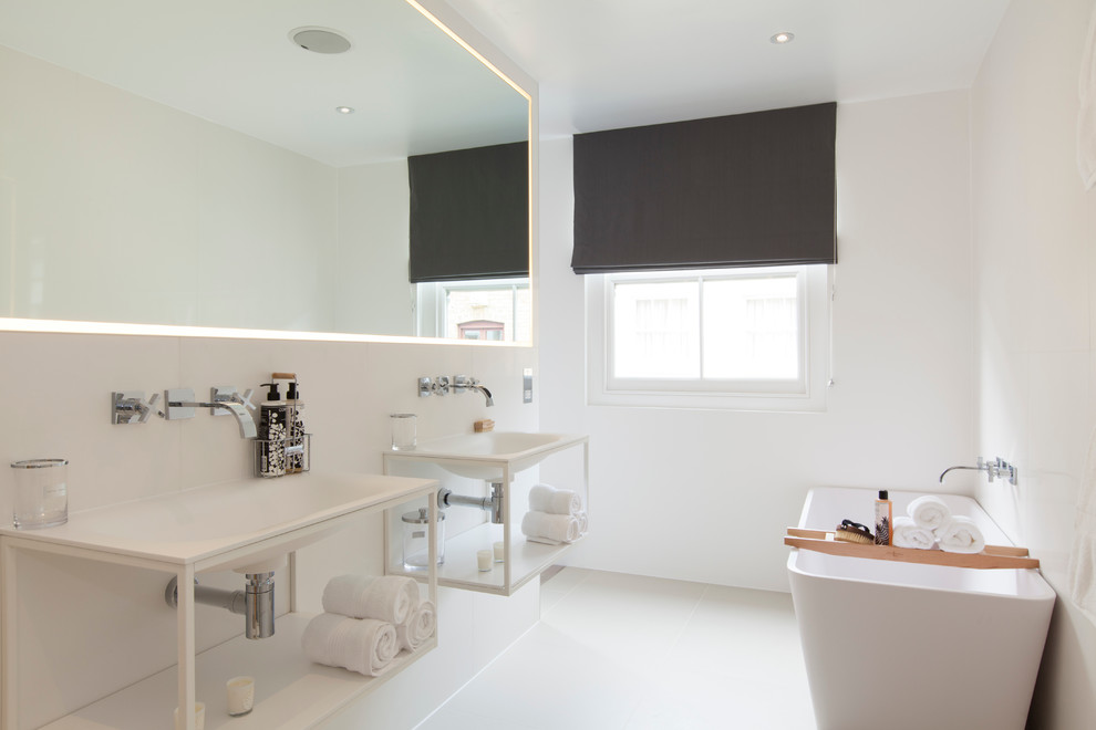 Inspiration for a medium sized contemporary ensuite bathroom in London with a wall-mounted sink, open cabinets, white cabinets, a freestanding bath, white walls and ceramic flooring.