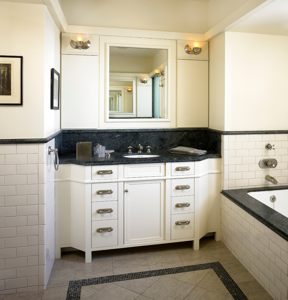 Foto di una piccola stanza da bagno padronale american style con consolle stile comò, ante con finitura invecchiata, vasca ad angolo, piastrelle grigie, pareti beige, top in marmo e lavabo sottopiano