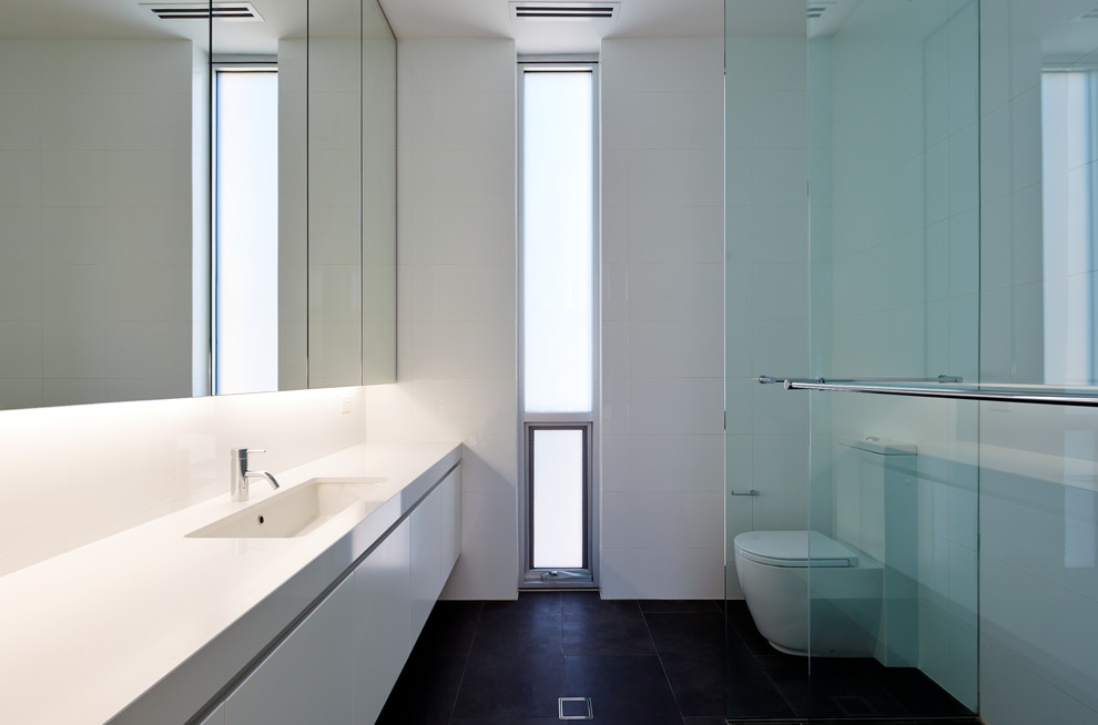 This is an example of a large contemporary ensuite bathroom in Adelaide with a submerged sink, recessed-panel cabinets, white cabinets, engineered stone worktops, a corner shower, a one-piece toilet, white tiles, ceramic tiles, white walls and porcelain flooring.