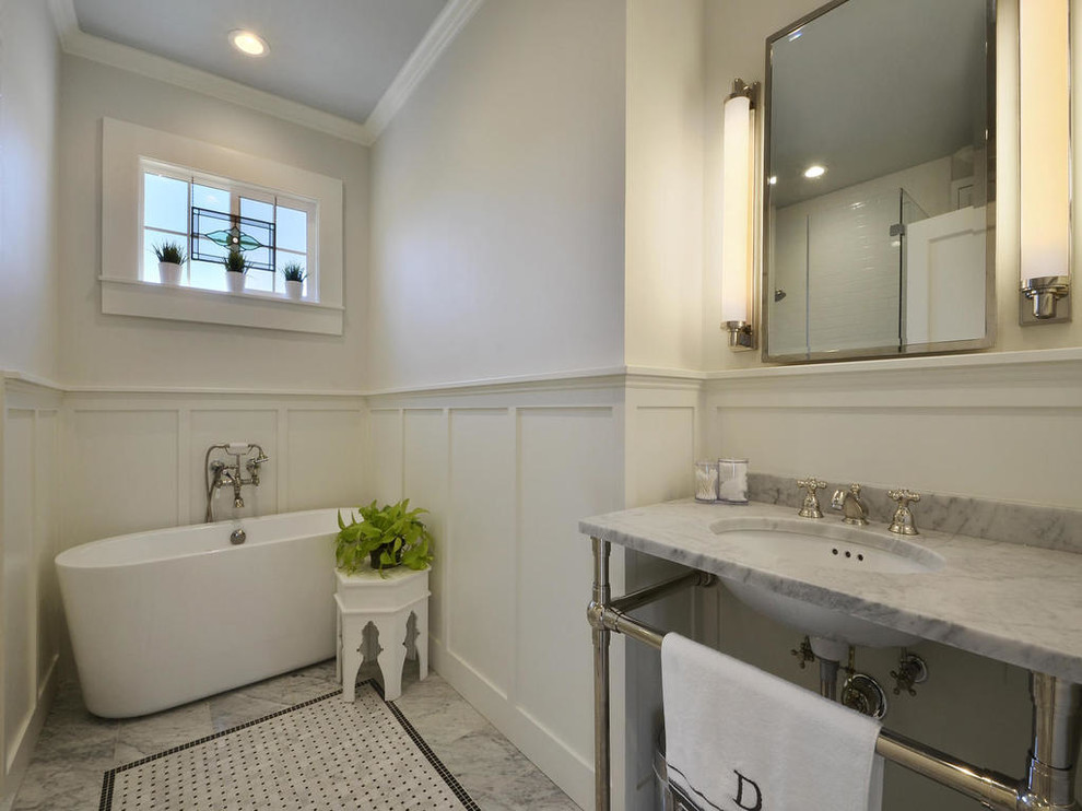 Cette photo montre une salle de bain principale chic avec un lavabo encastré, un plan de toilette en marbre, une baignoire indépendante, WC à poser, un carrelage de pierre, un mur blanc et un sol en marbre.