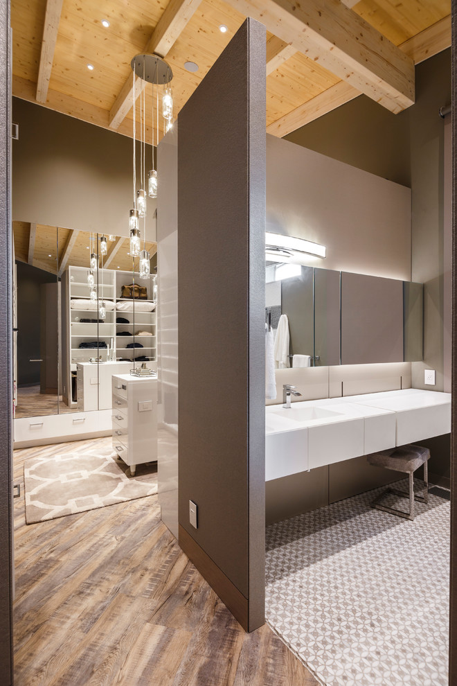 Cette image montre une salle de bain principale design avec des portes de placard blanches, WC suspendus, un mur gris, un lavabo intégré et aucune cabine.