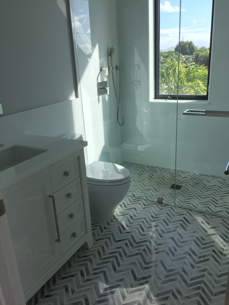 Inredning av ett modernt mellanstort badrum för barn, med ett undermonterad handfat, luckor med infälld panel, vita skåp, marmorbänkskiva, en kantlös dusch, en toalettstol med hel cisternkåpa, grå kakel, porslinskakel, grå väggar och marmorgolv