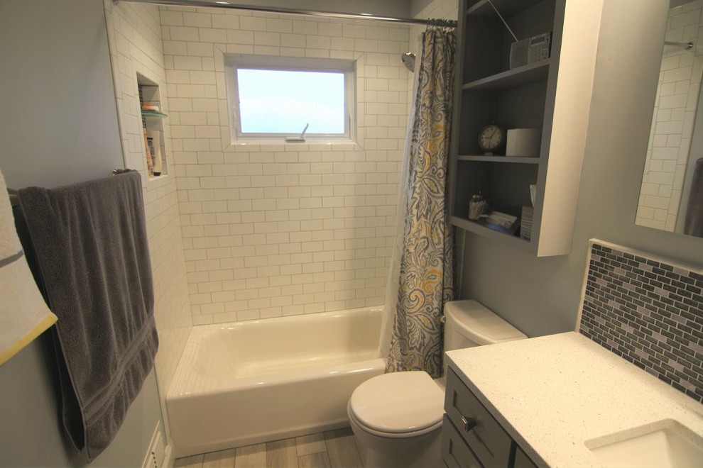 Cette photo montre une salle de bain principale chic de taille moyenne avec un placard avec porte à panneau encastré, des portes de placard grises, une baignoire en alcôve, un combiné douche/baignoire, WC à poser, un carrelage blanc, des carreaux de céramique, un mur gris, parquet peint, un lavabo encastré, un sol gris et une cabine de douche avec un rideau.