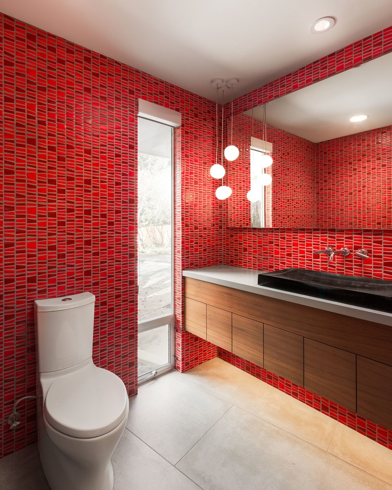 Стильный дизайн: ванная комната в современном стиле с плоскими фасадами, темными деревянными фасадами, раздельным унитазом, красными стенами и накладной раковиной - последний тренд