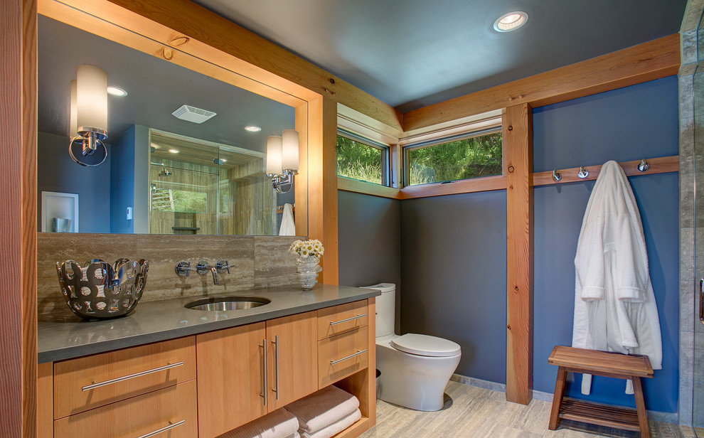 Corner shower - mid-sized rustic 3/4 porcelain tile and brown floor corner shower idea in Seattle with light wood cabinets, flat-panel cabinets, a two-piece toilet, blue walls, an undermount sink, quartz countertops, a hinged shower door and gray countertops