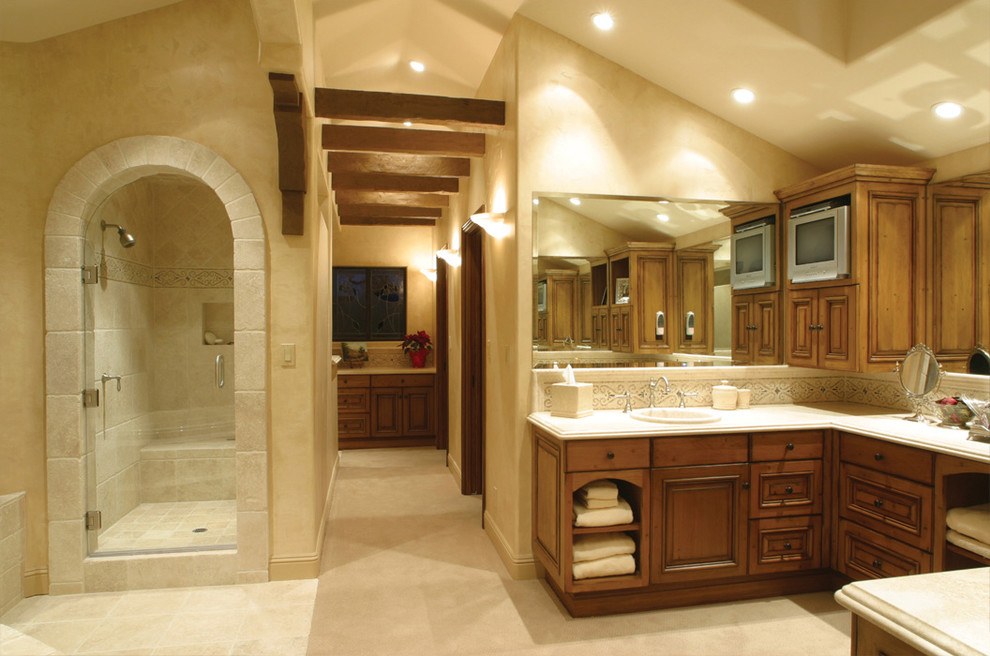 Bild på ett medelhavsstil badrum, med ett nedsänkt handfat, luckor med upphöjd panel, skåp i mellenmörkt trä, en dusch i en alkov, beige kakel och stenkakel