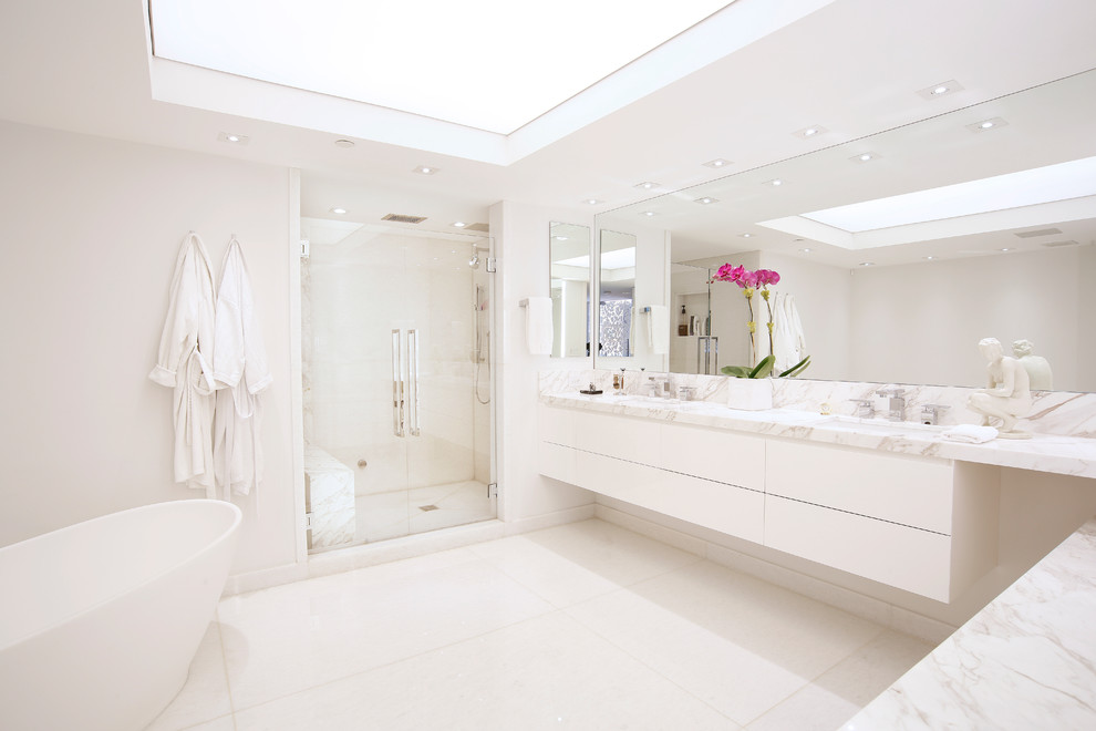 Inspiration pour une douche en alcôve principale design avec un placard à porte plane, des portes de placard blanches, une baignoire indépendante et un lavabo encastré.
