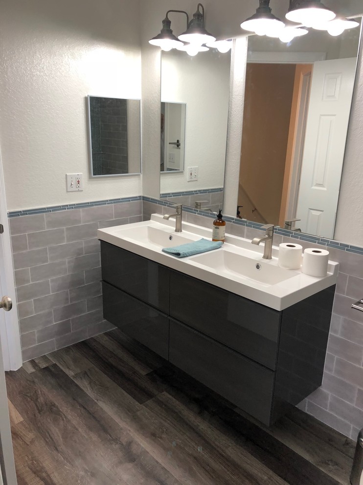 Exempel på ett mellanstort modernt vit vitt en-suite badrum, med släta luckor, grå skåp, en dusch/badkar-kombination, en toalettstol med separat cisternkåpa, grå kakel, glaskakel, gula väggar, vinylgolv, ett väggmonterat handfat, träbänkskiva, grått golv och dusch med gångjärnsdörr