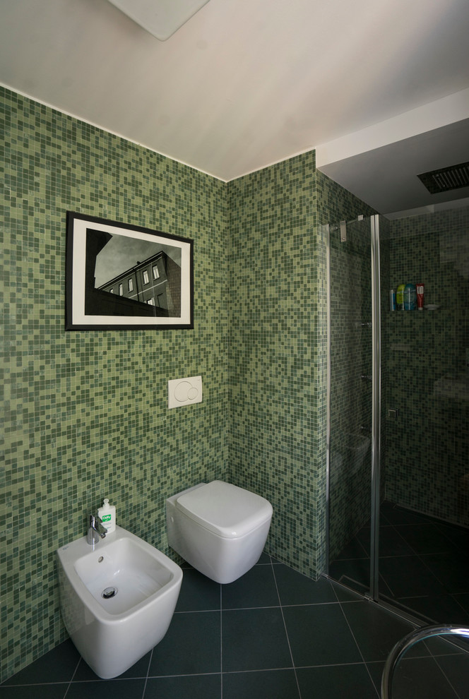 Foto på ett litet funkis grön en-suite badrum, med kaklad bänkskiva, en dusch i en alkov, en toalettstol med separat cisternkåpa, grön kakel, mosaik, gröna väggar, klinkergolv i keramik, släta luckor, skåp i ljust trä, ett avlångt handfat, grönt golv och dusch med gångjärnsdörr