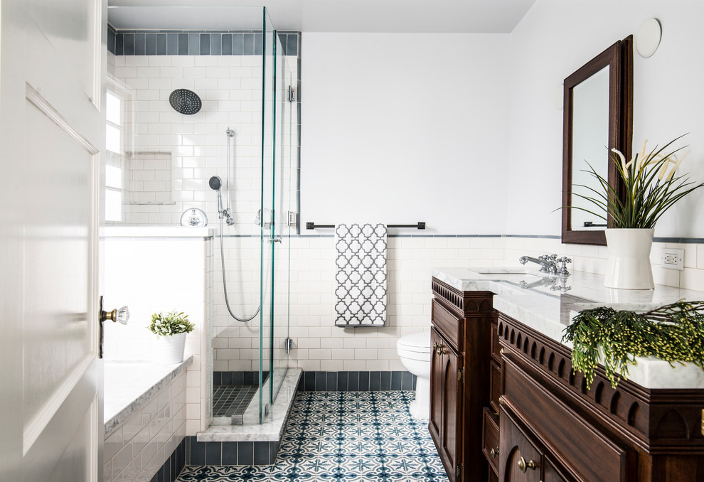 This is an example of a traditional bathroom in Los Angeles with dark wood cabinets, an alcove bath, an alcove shower, white tiles, metro tiles, white walls and recessed-panel cabinets.