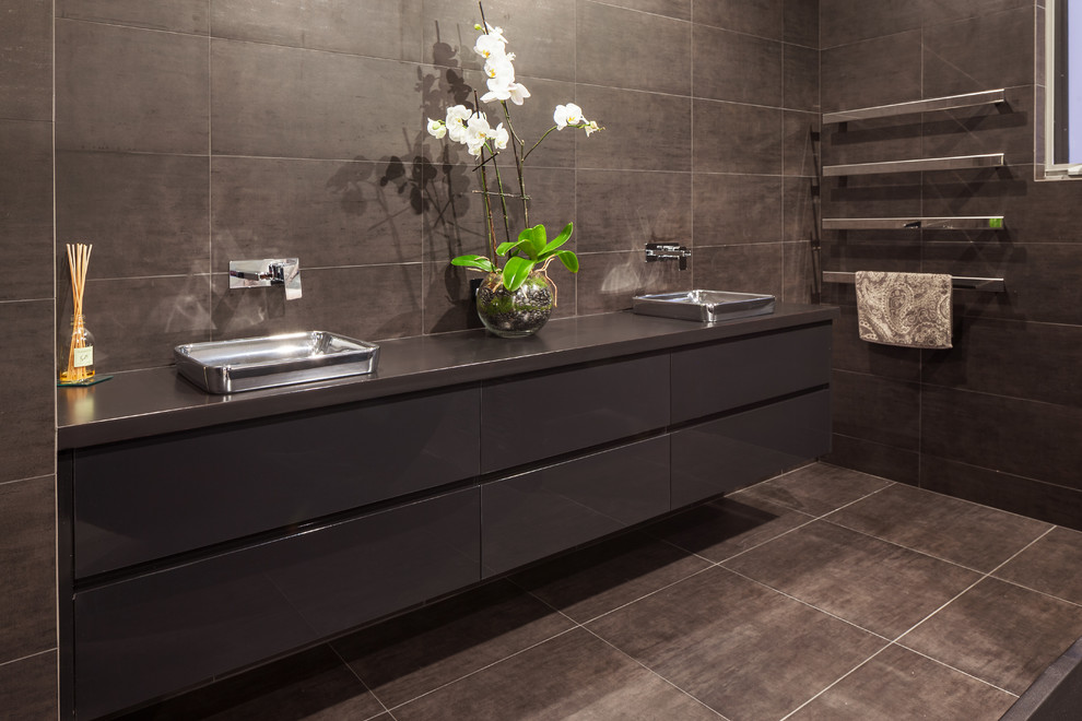 Cette image montre une salle de bain minimaliste avec un placard à porte plane, des portes de placard noires, un plan de toilette en bois et une baignoire indépendante.