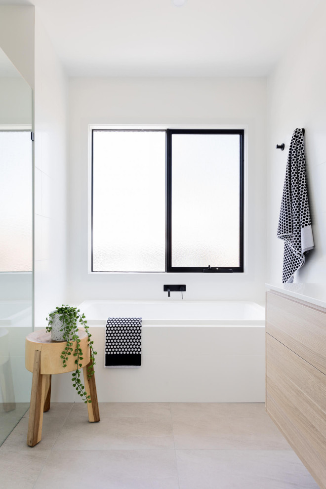 Modernes Badezimmer mit flächenbündigen Schrankfronten, hellen Holzschränken, Badewanne in Nische, weißer Wandfarbe, grauem Boden und weißer Waschtischplatte in Melbourne