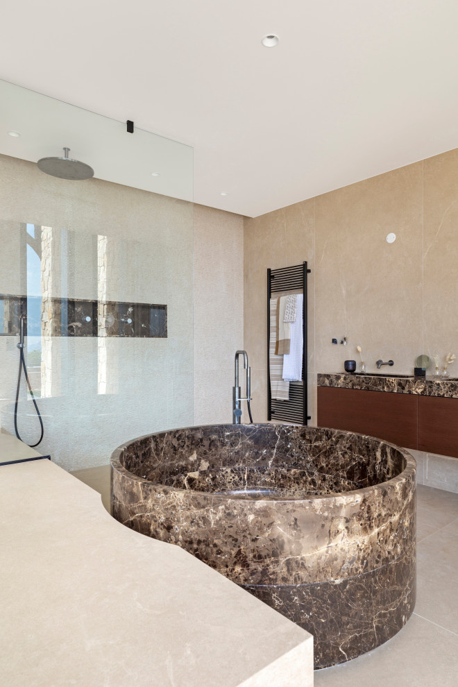 Idéer för ett mycket stort modernt brun en-suite badrum, med ett fristående badkar, en kantlös dusch, beige kakel, marmorkakel, marmorbänkskiva, släta luckor, skåp i mörkt trä, beiget golv och med dusch som är öppen