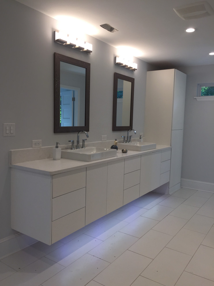 Bild på ett mellanstort funkis grå grått en-suite badrum, med släta luckor, vita skåp, grå kakel, grå väggar, klinkergolv i porslin, ett fristående handfat, bänkskiva i kvarts och vitt golv