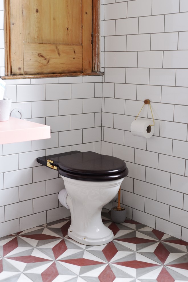 Photo of a medium sized classic family bathroom in London with raised-panel cabinets, medium wood cabinets, a claw-foot bath, a walk-in shower, a one-piece toilet, white tiles, ceramic tiles, white walls, ceramic flooring, a trough sink, solid surface worktops, multi-coloured floors and an open shower.