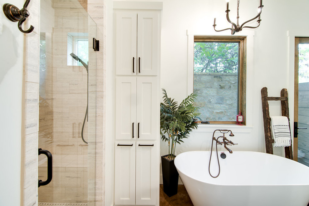 Пример оригинального дизайна: огромная главная ванная комната в стиле кантри с фасадами в стиле шейкер, белыми фасадами, отдельно стоящей ванной, душем в нише, раздельным унитазом, бежевой плиткой, керамогранитной плиткой, белыми стенами, бетонным полом, врезной раковиной, столешницей из гранита, коричневым полом, душем с распашными дверями и белой столешницей